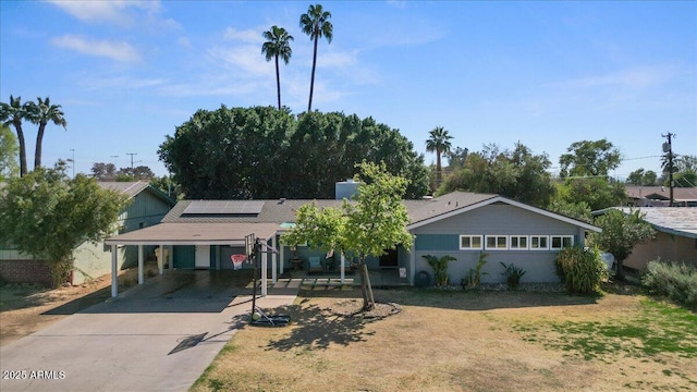 single story home featuring solar panels, a carport, and concrete driveway