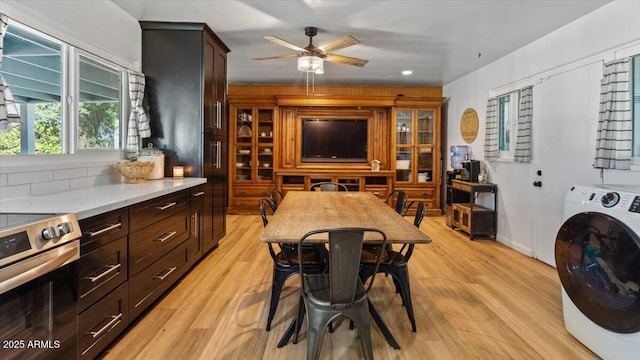 kitchen with stainless steel electric stove, washer / clothes dryer, light countertops, light wood-style flooring, and dark brown cabinetry