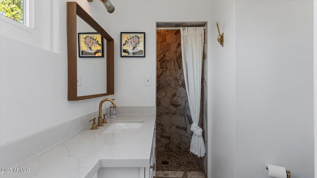 bathroom featuring tiled shower and vanity