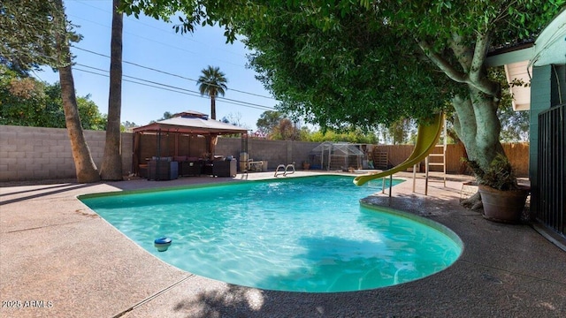 view of pool featuring a fenced backyard, a patio, a water slide, and a gazebo