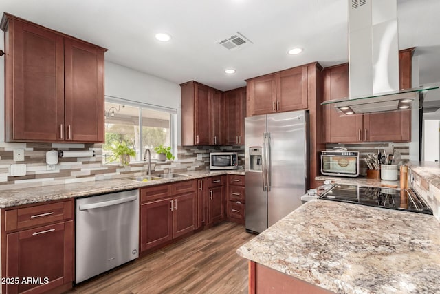 kitchen with visible vents, a sink, backsplash, stainless steel appliances, and island range hood