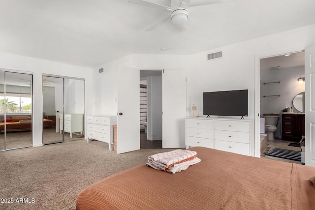 bedroom with carpet flooring, connected bathroom, two closets, and visible vents