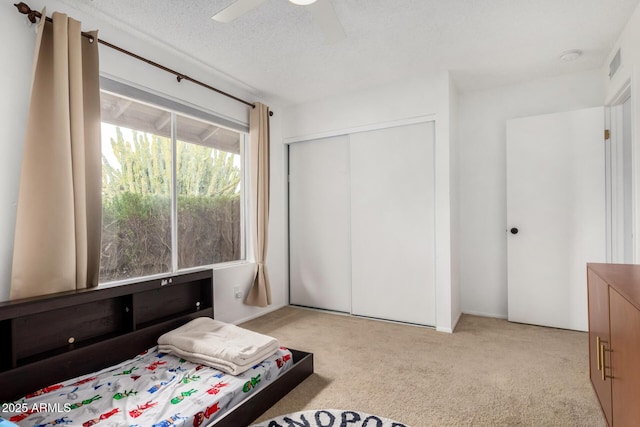 bedroom featuring visible vents, carpet, a closet, a textured ceiling, and a ceiling fan