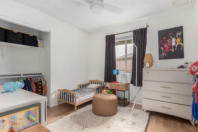 bedroom featuring visible vents, wood finished floors, a closet, a textured ceiling, and a ceiling fan