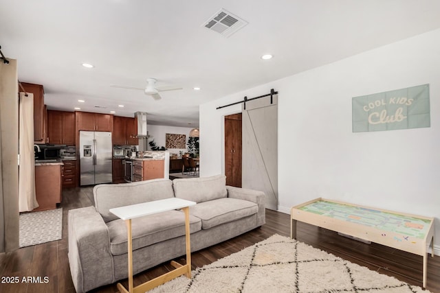 living area featuring visible vents, ceiling fan, a barn door, recessed lighting, and dark wood-style floors