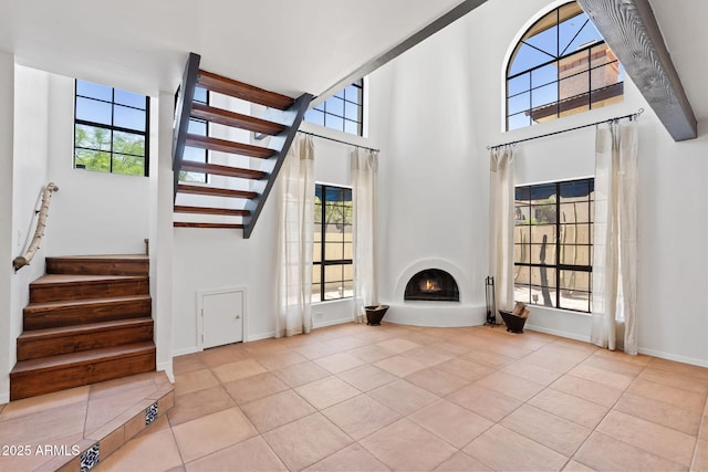 8844 S 51st St Unit 3, Phoenix, AZ 85044 - unfurnished living room with stairway, tile patterned floors, a lit fireplace, and a towering ceiling