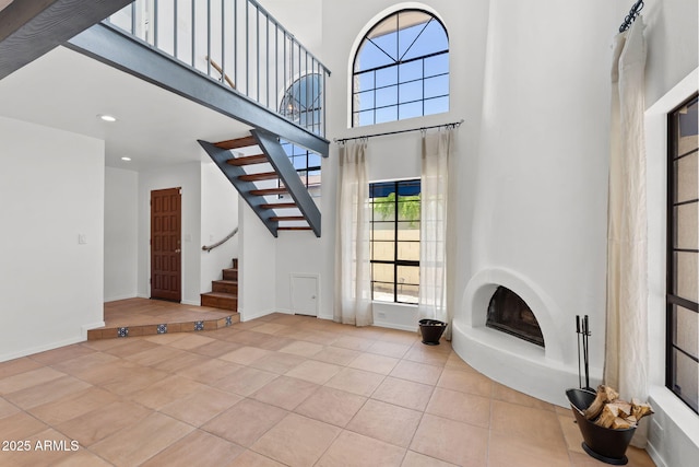 8844 S 51st St Unit 3, Phoenix, AZ 85044 - unfurnished living room featuring stairway, a high ceiling, a fireplace with raised hearth, and tile patterned flooring