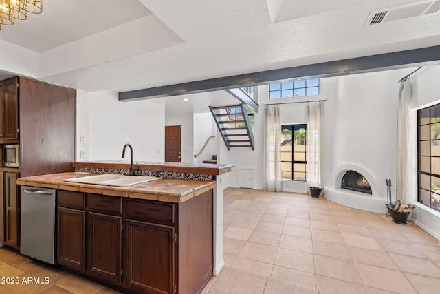 8844 S 51st St Unit 3, Phoenix, AZ 85044 - kitchen with tile countertops, visible vents, a sink, a warm lit fireplace, and light tile patterned flooring