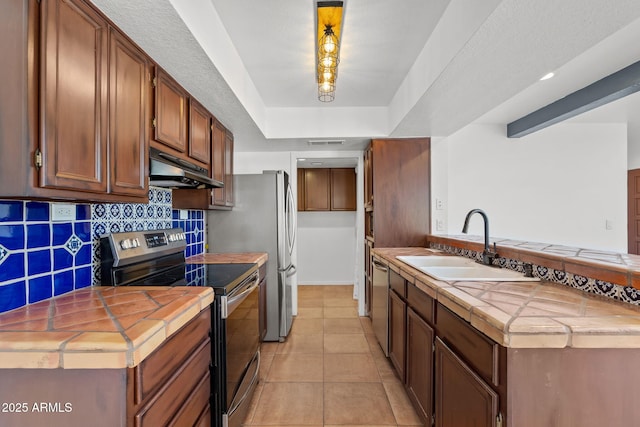 8844 S 51st St Unit 3, Phoenix, AZ 85044 - kitchen featuring tile counters, under cabinet range hood, a sink, appliances with stainless steel finishes, and backsplash