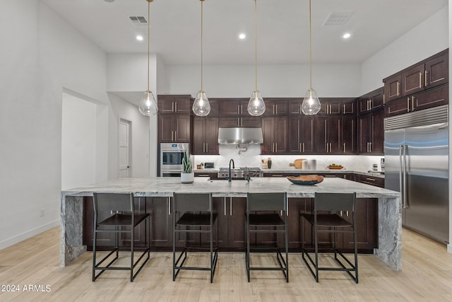 kitchen with under cabinet range hood, visible vents, stainless steel appliances, and a sink