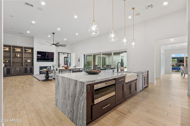 kitchen with a warm lit fireplace, visible vents, a sink, and light wood-style flooring