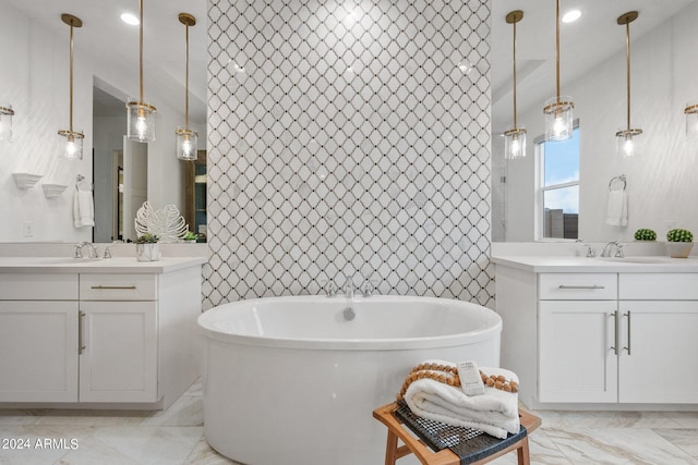 bathroom with a soaking tub, two vanities, a sink, and marble finish floor