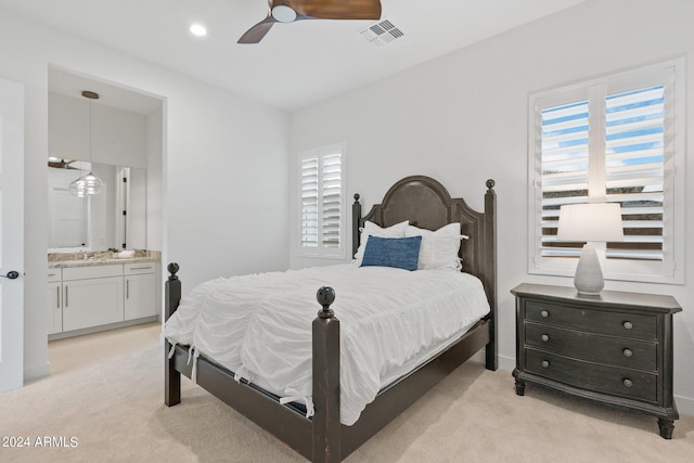 bedroom with ceiling fan, ensuite bath, visible vents, and light colored carpet