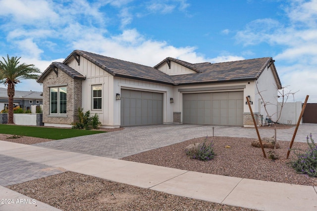 view of front of home with a garage, decorative driveway, board and batten siding, and brick siding