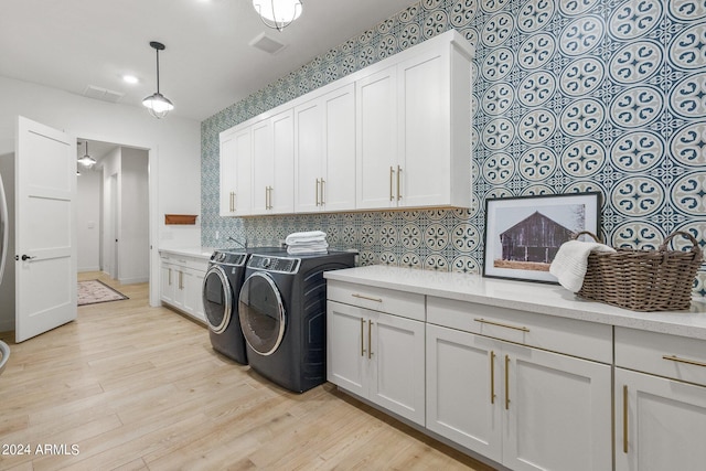 laundry room with visible vents, light wood-type flooring, washing machine and clothes dryer, and cabinet space