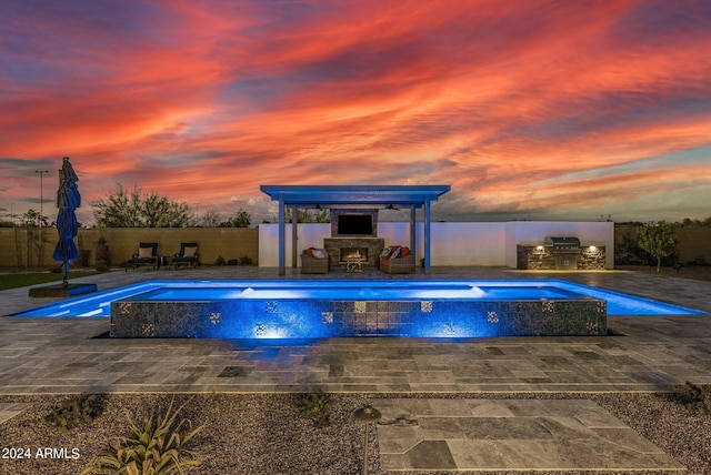 view of pool featuring a patio, a fenced backyard, an outdoor stone fireplace, area for grilling, and a fenced in pool