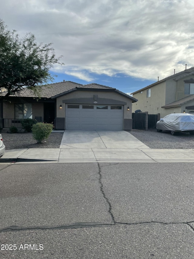 view of front of house with stucco siding, an attached garage, driveway, and a tile roof