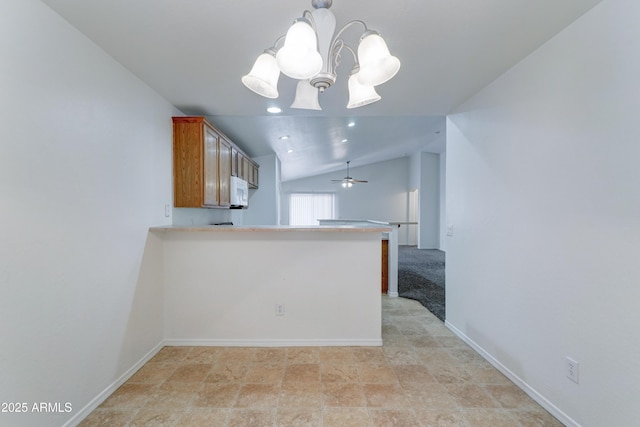 kitchen with white microwave, decorative light fixtures, vaulted ceiling, brown cabinets, and a peninsula