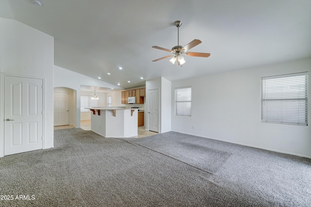 unfurnished living room with light carpet, a ceiling fan, recessed lighting, arched walkways, and lofted ceiling