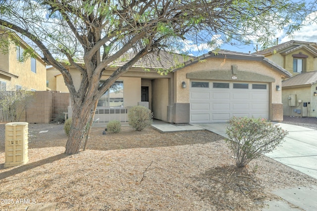 view of front of property with concrete driveway, an attached garage, fence, and stucco siding