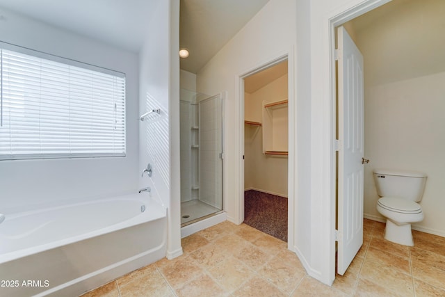 bathroom featuring a stall shower, a walk in closet, a garden tub, toilet, and tile patterned floors