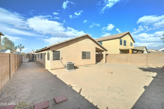 back of property featuring stucco siding, a patio, central AC, and a fenced backyard