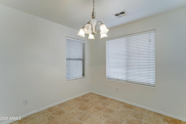 empty room featuring a notable chandelier, visible vents, and baseboards