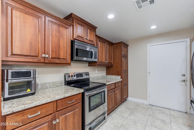 kitchen featuring stainless steel appliances, brown cabinetry, light stone counters, recessed lighting, and light tile patterned floors