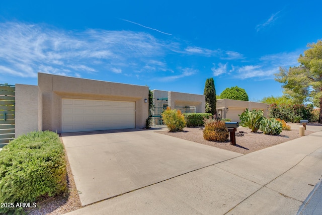 southwest-style home featuring stucco siding, driveway, fence, a gate, and an attached garage