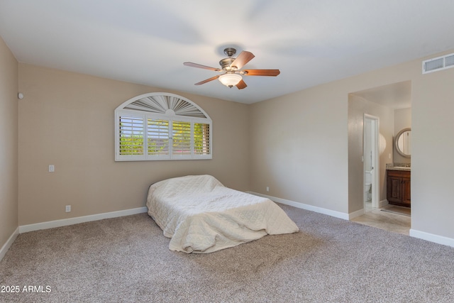 bedroom featuring light carpet, baseboards, ceiling fan, and ensuite bathroom