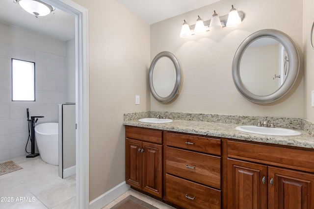 bathroom featuring tile patterned flooring, double vanity, a freestanding tub, and baseboards