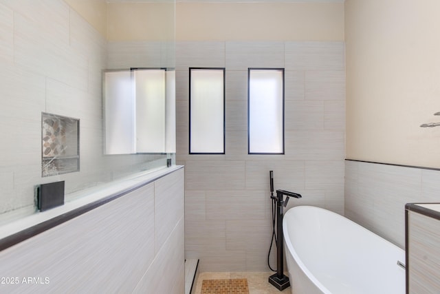 bathroom featuring a freestanding tub and tile walls