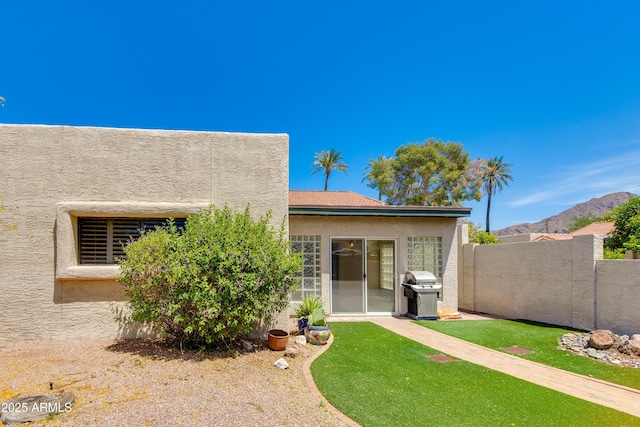 rear view of house with stucco siding, fence, and a mountain view