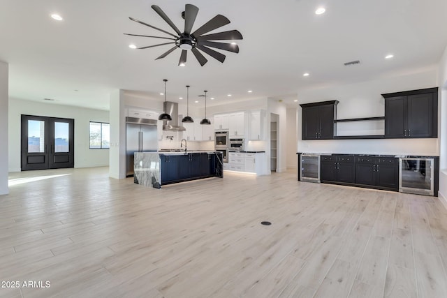 unfurnished living room with beverage cooler, a sink, light wood-style flooring, and recessed lighting