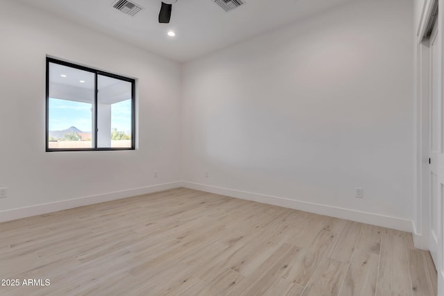 empty room with a ceiling fan, light wood-type flooring, visible vents, and baseboards