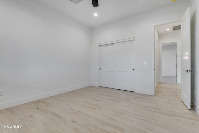 unfurnished bedroom featuring light wood-style floors, a closet, visible vents, and baseboards