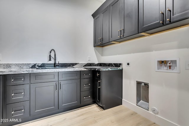 laundry area with cabinet space, hookup for a gas dryer, hookup for a washing machine, light wood-style floors, and a sink