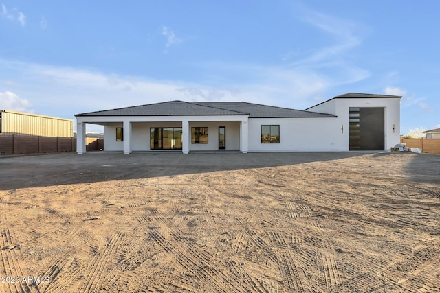 view of front facade featuring stucco siding, fence, and a patio