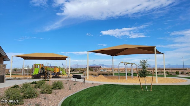 view of playground featuring a mountain view and a lawn