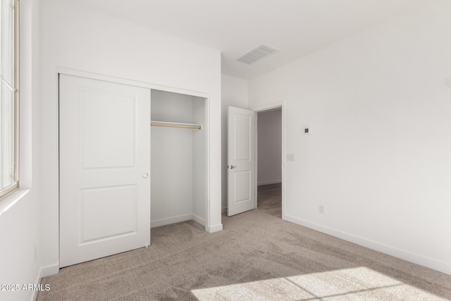 unfurnished bedroom featuring light carpet and a closet