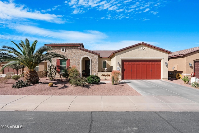 mediterranean / spanish-style home with a garage, concrete driveway, stone siding, a tiled roof, and stucco siding