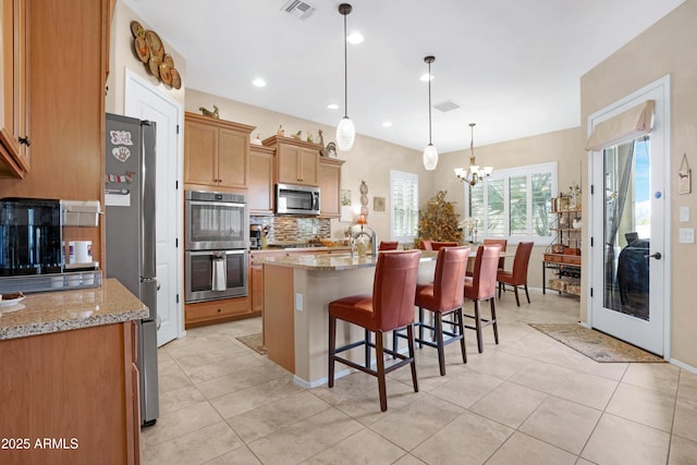 kitchen featuring a kitchen island with sink, visible vents, stainless steel appliances, and decorative backsplash