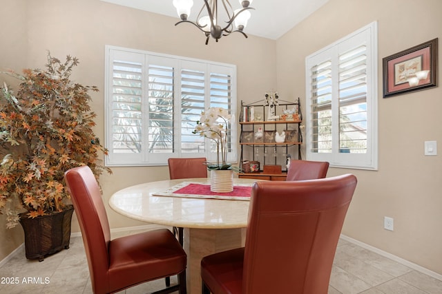 dining room with a notable chandelier, light tile patterned flooring, and baseboards