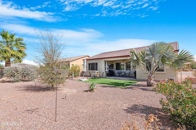 rear view of house with a patio area, fence, and stucco siding