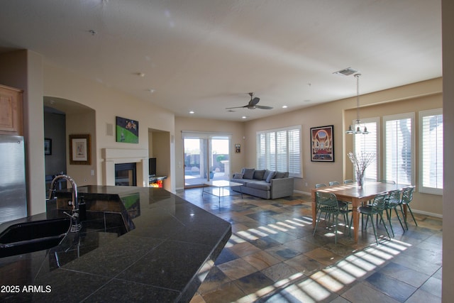 14045 E Geronimo Rd, Scottsdale, AZ 85259 - living room featuring arched walkways, a glass covered fireplace, ceiling fan with notable chandelier, recessed lighting, and baseboards