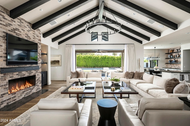 living room with a fireplace, dark hardwood / wood-style floors, a chandelier, and lofted ceiling with beams