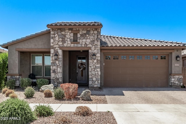 view of front of house with stone siding, a tile roof, driveway, an attached garage, and stucco siding