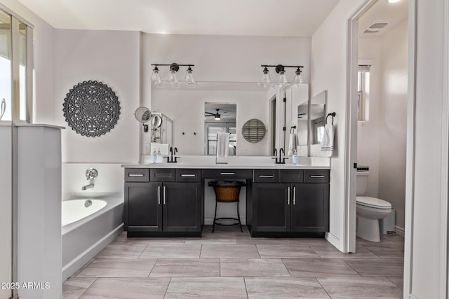 bathroom with ceiling fan, a bath, double vanity, and healthy amount of natural light