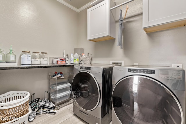 laundry room featuring cabinet space, ornamental molding, washer and dryer, and light wood-style flooring
