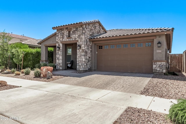 view of front of house with a tile roof, driveway, stucco siding, stone siding, and an attached garage